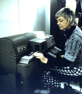 NWS employee at a teletype machine with paper tape reader, circa 1970s