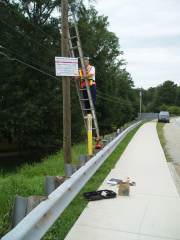 [Kent Frantz, Service Hydrologist, Weather Forecast Office Peachtree City, installs a high water mark sign by the Powders Springs Road bridge. ]