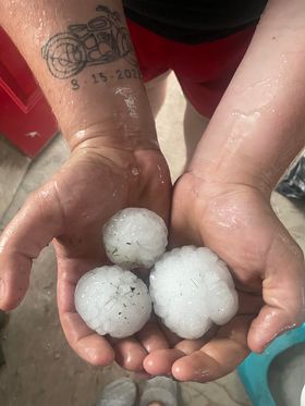 Someone holding three large hailstones.