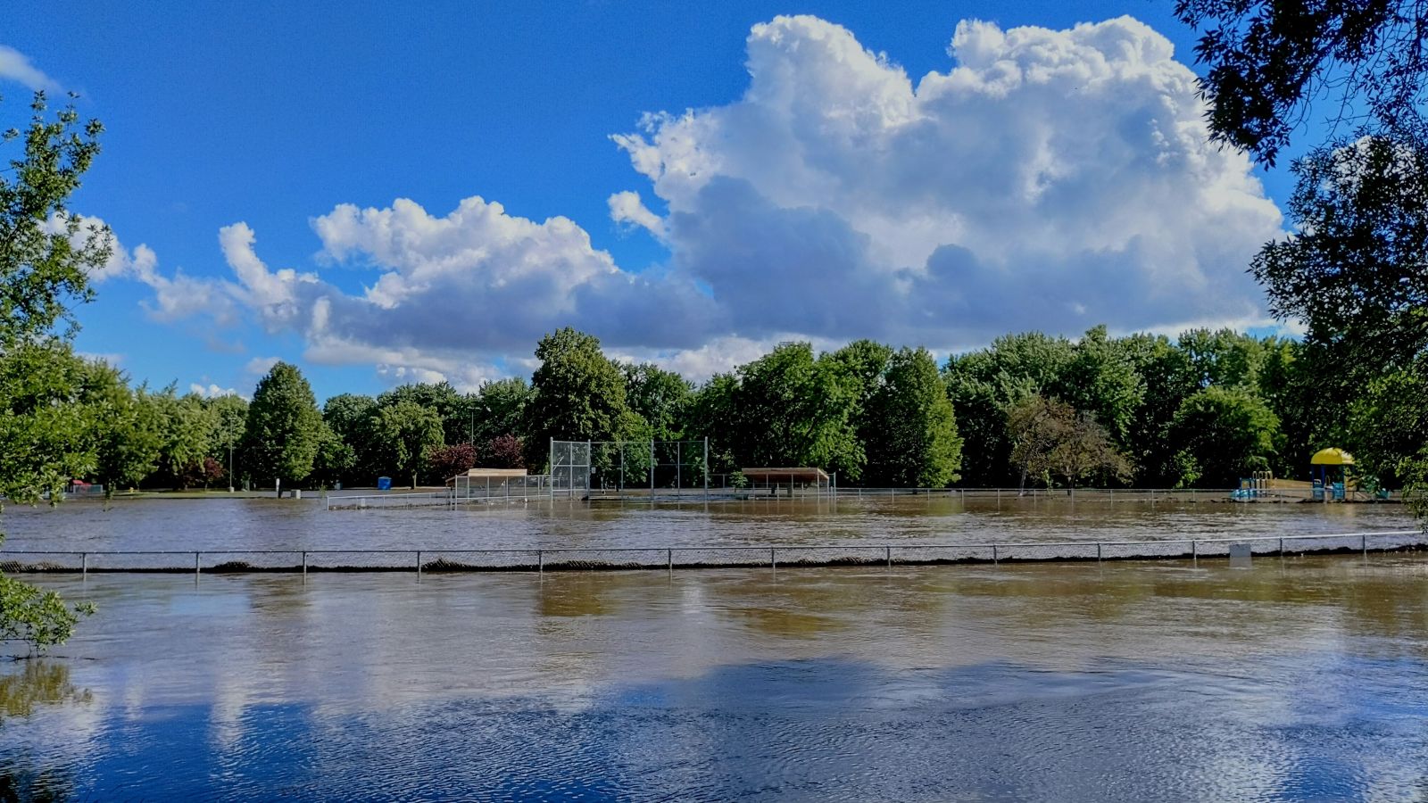 Photo of river flood waters near the top of a ball field outfield fence at Cherry Rock Park in eastern Sioux Falls SD