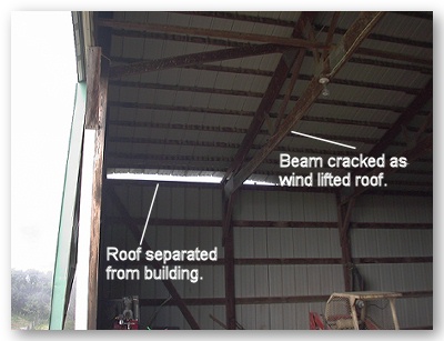 Photo of separated roof and cracked roof truss from within the damaged building.