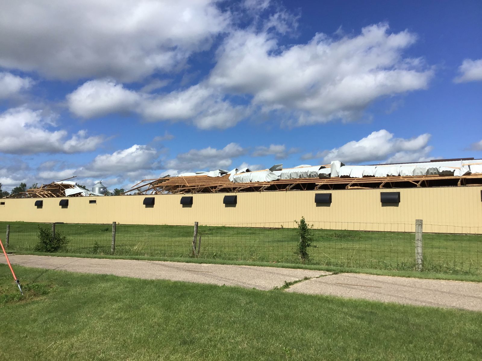 Photo of long pole barn with most of the roofing materials blown off