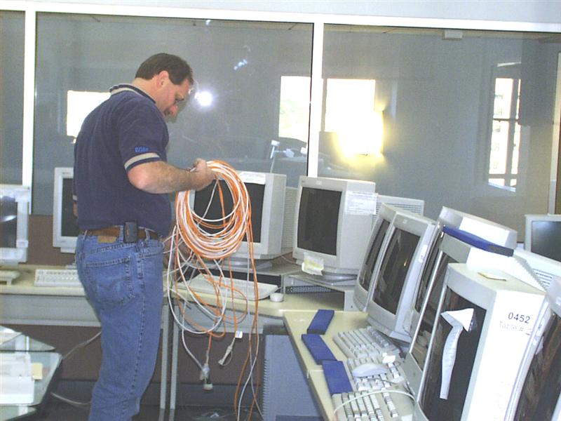 A picture of a worker laying cable under the floor in our main operations room.