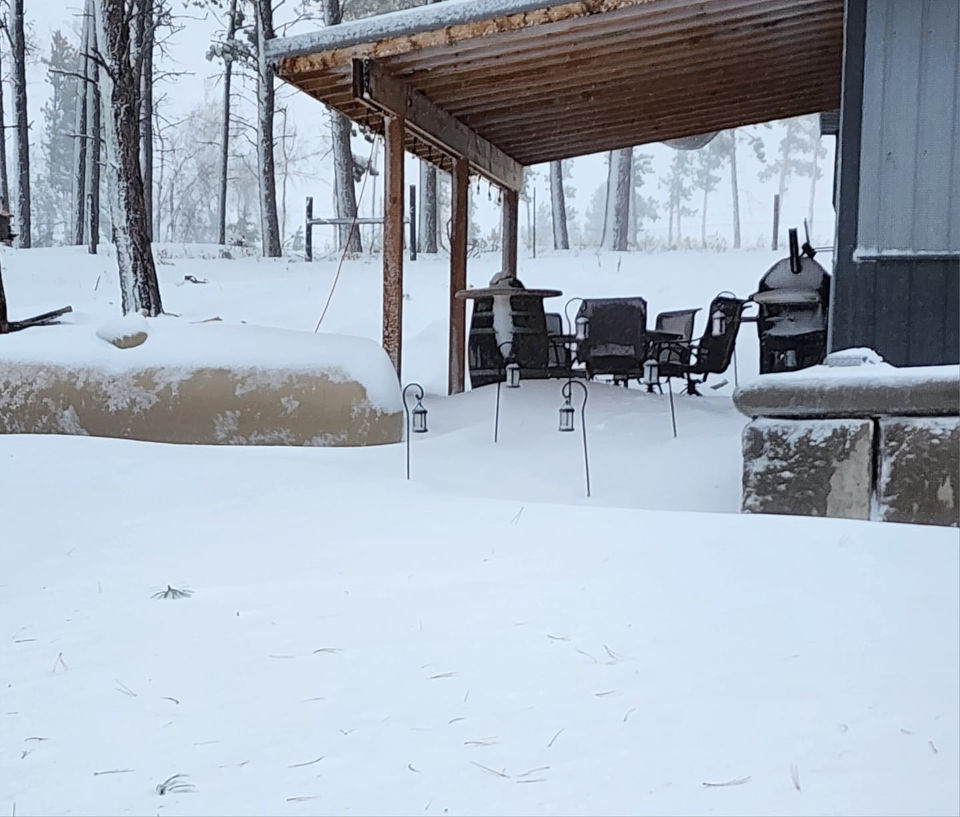 Snow-covered backyard with awning coming off a house